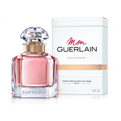 Elegant Mon Guerlain perfume bottle with its clear, quadrilobe design and gold accents, representing sophistication in woody fragrances for her.